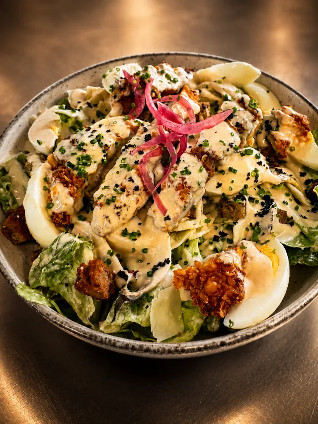 Salade César au poulet, œufs fermiers, copeaux de parmesan et oignons rouges marinés