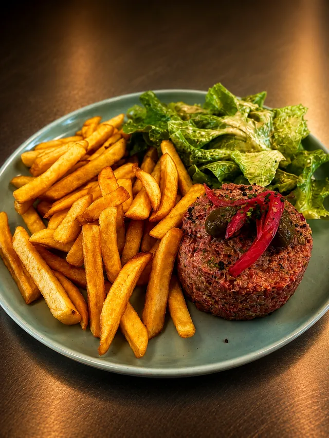Tartare de bœuf coupé au couteau, câpres et oignons rouges, servi avec frites maison et salade